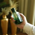 Zimaya Oscar by Zimaya 100ml EDP Men — A hand holding a green glass perfume bottle with a dark green cap, showing the "OSCAR eau de parfum" label and a bird logo.