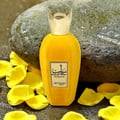 Zimaya Rabab Pulp by Zimaya 100 ml EDP Unisex — Botol minyak wangi baldu kuning dengan penutup emas, dikelilingi kelopak bunga kuning dan batu kelabu besar.