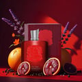 Zimaya Red Carpet Paragon EDP 100ml — Red perfume bottle with embossed crest, silver cap, red striped box, oranges, blood orange slices, lavender, and peppercorns on a red surface.