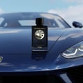 Zimaya Reverie Aqua by Zimaya 100ml EDP Men — Black perfume bottle with gold sun and wave emblem, placed on the hood of a dark blue luxury sports car.