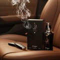 Zimaya Taraf Black by Zimaya 100ml EDP Men — Botol dan kotak minyak wangi hitam terletak di atas tempat duduk kereta kulit coklat, bersama kunci kereta dan asap naik.