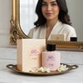 Yaa Umree by Zimaya EDP 100 ml Women — A pink perfume bottle and its box sit on a decorative tray with white flowers, reflected in an ornate mirror behind a woman.