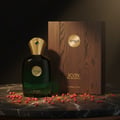 Zimaya Icon by Zimaya 100ml EDP for Men — Botol minyak wangi kaca hijau bertudung emas dan permata hijau, sebelah kotak bertekstur kayu, bertabur lada merah di atas permukaan marmar.