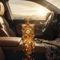 Zimaya Siada Nova by Zimaya 100 ml EDP — A golden perfume bottle with intricate patterns sits on a car's center console, with amber-like droplets and wooden pieces spilling out. A decorative dagger and patterned cloth are visible.