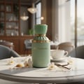 Gulf Orchid Honeymoon by Gulf Orchid Unisex 100ml — A green perfume bottle with gold accents sits on a marble table, surrounded by orchids, vanilla beans, and sugar crystals. A steaming cup of tea is in the background.