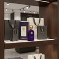 Maison Alhambra Philos Centro 100ml EDP — Purple perfume bottle with gold cap and ring, displayed with matching gift bags and a patterned box on a wooden shelf.