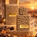French Avenue Sacred Smoke EDP Unisex — Botol dan kotak bertekstur anyaman, diletakkan di atas batu bersama kayu oud dan resin amber, latar belakang matahari terbenam gurun dengan kepulan asap.