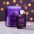 Ard Al Zaafaran Sama Dubai 100ml — A purple perfume bottle and its matching box are displayed on a reflective surface, with a bokeh background of warm lights. | Ard Al Zaafaran Sama Dubai 100ml — Botol minyak wangi ungu dan kotaknya yang sepadan dipaparkan di permukaan reflektif, dengan latar belakang bokeh cahaya