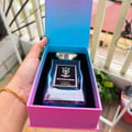Bujairami Soul Fusion Intense — A hand holding a blue glass perfume bottle with a gold cap, presented in a pink and blue gradient box, with text visible on the inside lid.