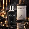 TADangel Status by TADangel 100ml EDP Men — Botol minyak wangi hitam dengan penutup perak, di atas permukaan marmar bersama gelas wiski dan butang lengan di latar belakang, dengan kesan asap.
