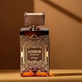 Zimaya Amber Is Great Eau De Parfum 100ml — A rectangular amber glass perfume bottle with ornate gold geometric detailing and the text "AMBER IS GREAT zimaya" is displayed against a warm brown background with dramatic shadow lines | Zimaya Amber Is Great Eau De Parfum 100ml — Sebotol minyak wangi kaca berwarna ambar