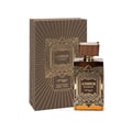 Zimaya Amber Is Great Eau De Parfum 100ml — A brown box with gold geometric patterns stands next to a matching brown glass perfume bottle with a ribbed brown cap and gold geometric label. | Zimaya Amber Is Great Eau De Parfum 100ml — Kotak coklat dengan corak geometri emas berdiri di sebelah botol minyak wangi kaca