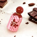 Grandeur Tubbees Chocolate Fudge by Grandeur 50ml EDP — A pink and white striped perfume bottle with chocolate drizzle design and a red spherical cap, surrounded by chocolate pieces and cocoa beans on a textured surface. | Grandeur Tubbees Chocolate Fudge by Grandeur 50ml EDP — Botol minyak wangi berjalur merah jambu