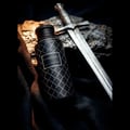 Vanguard by Maison Asrar 100ml EDP Unisex — Botol hitam bermotif dengan aksen perak, diletakkan bersebelahan pedang zaman pertengahan di atas permukaan berbatu dan fabrik gelap.